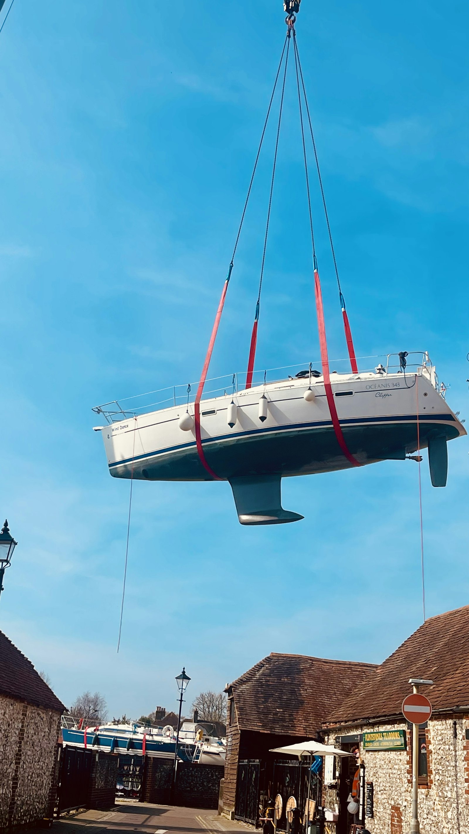 A yacht in crane slings being lifted out of the water