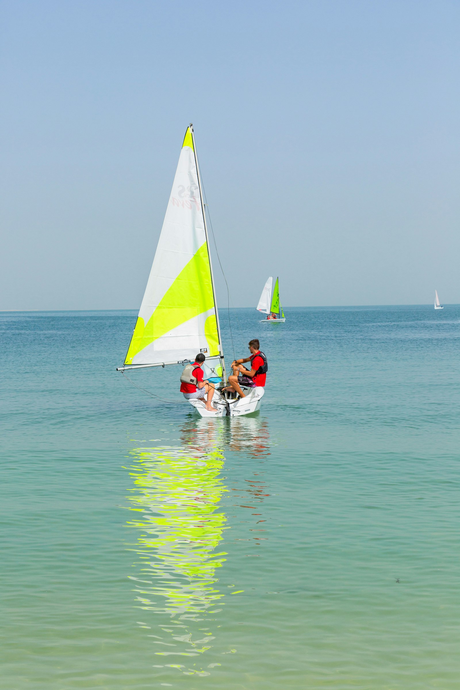 Two beginner dinghies on flat turquoise water