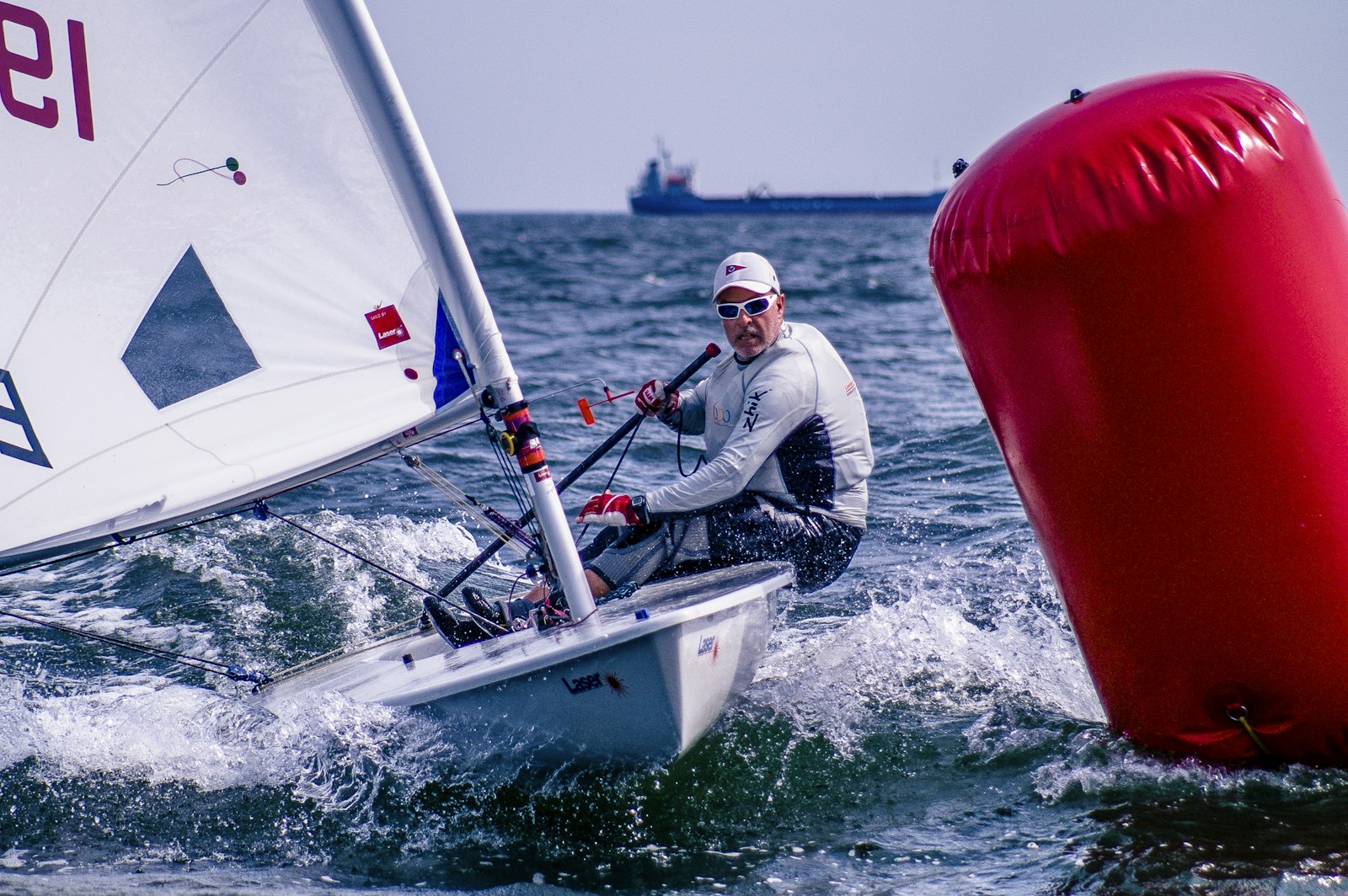 A dinghy sailor rounding a red racing mark