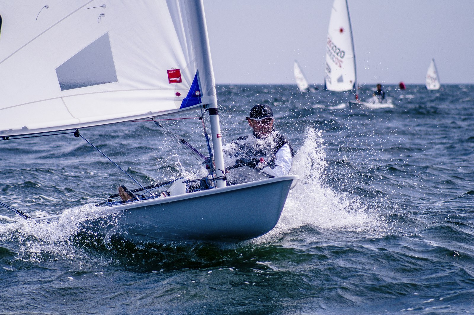 A Laser dinghy sailing with the fleet behind